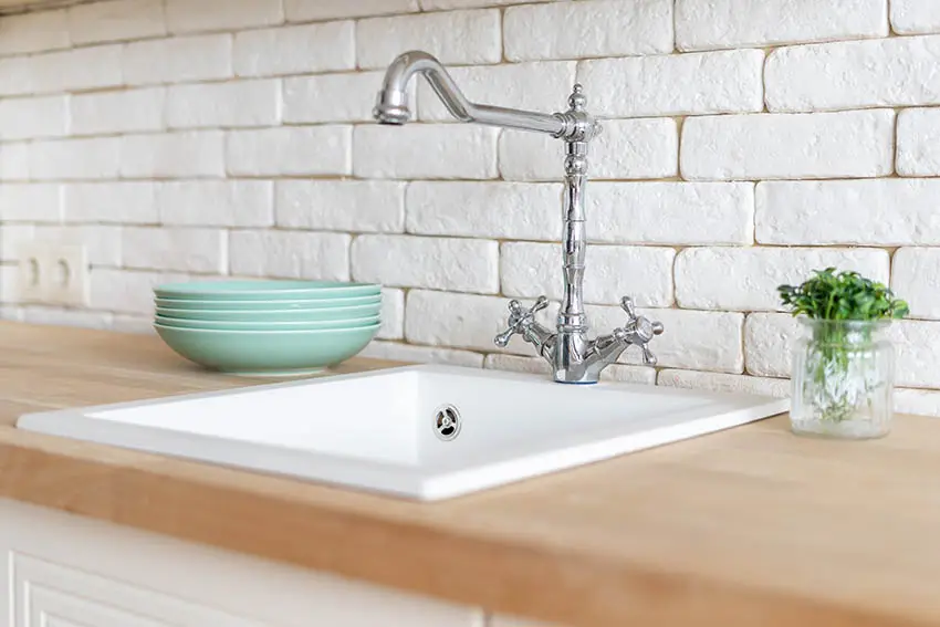 Kitchen with stone backsplash single basin sink wood countertop