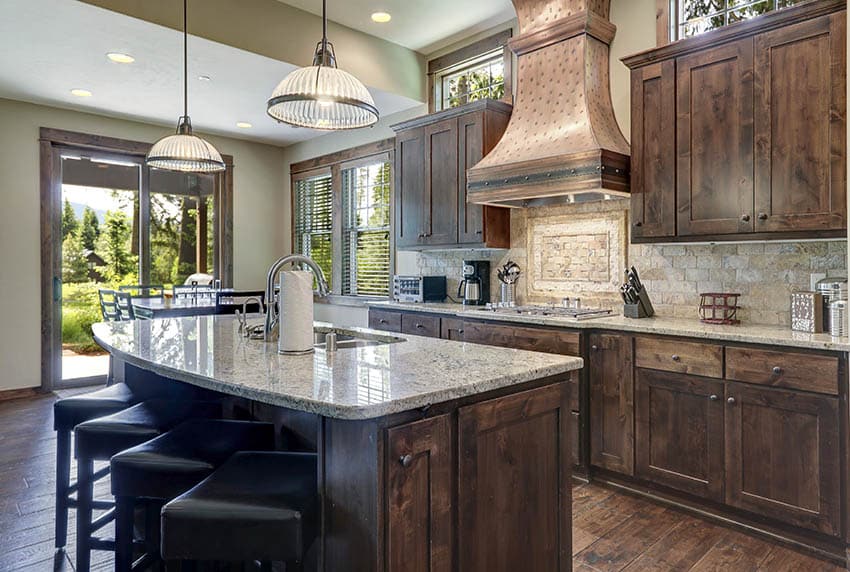 Kitchen with travertine backsplash, granite countertops and dark wood cabinets