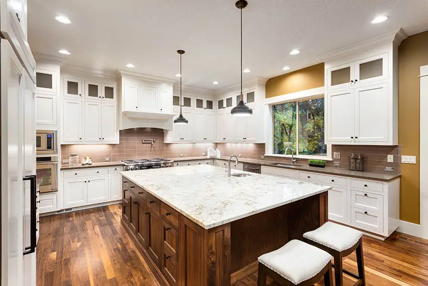 Kitchen with white granite countertops white cabinets brown island and two sinks