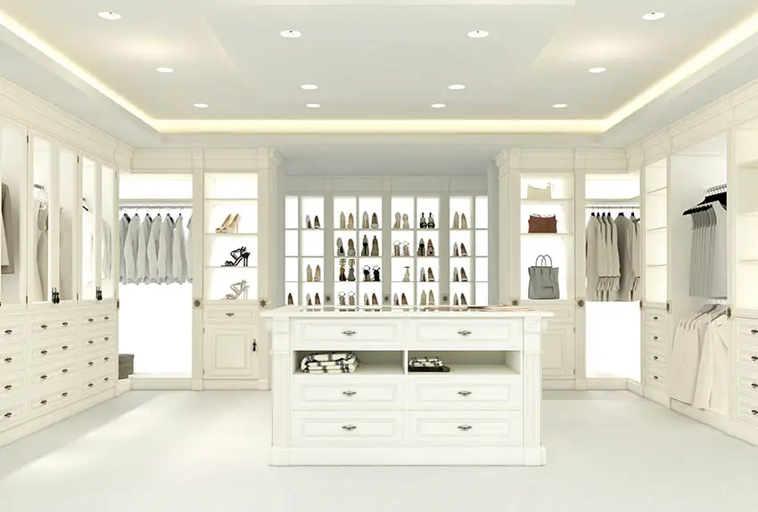 Large walk in closet with lighted shoe racks and tray ceiling