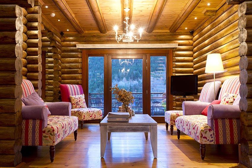 Living room with log walls, pink furniture set and chandelier