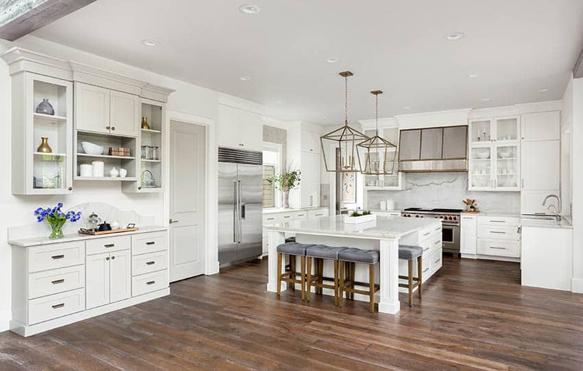 Luxury white cabinet kitchen with dark wood flooring and large marble island