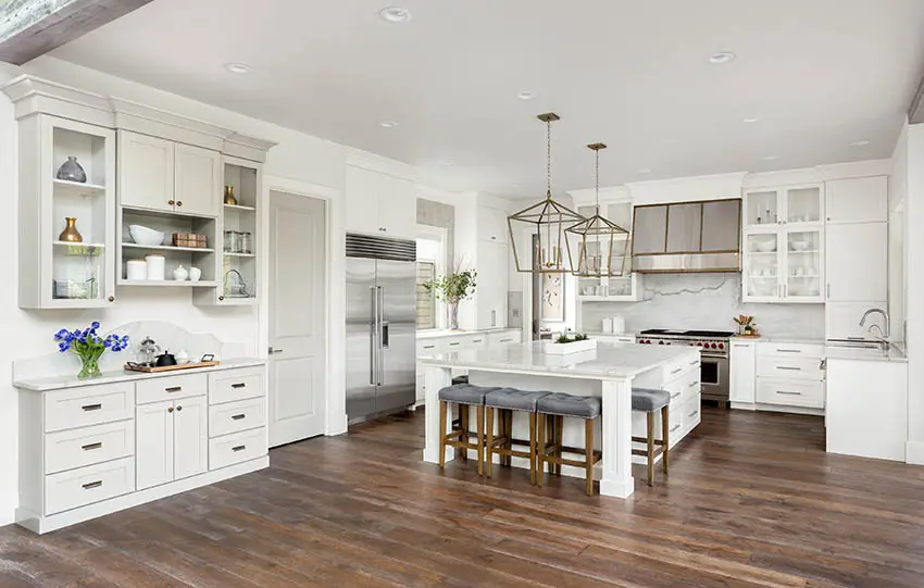Luxury white cabinet kitchen with dark wood flooring and large marble island