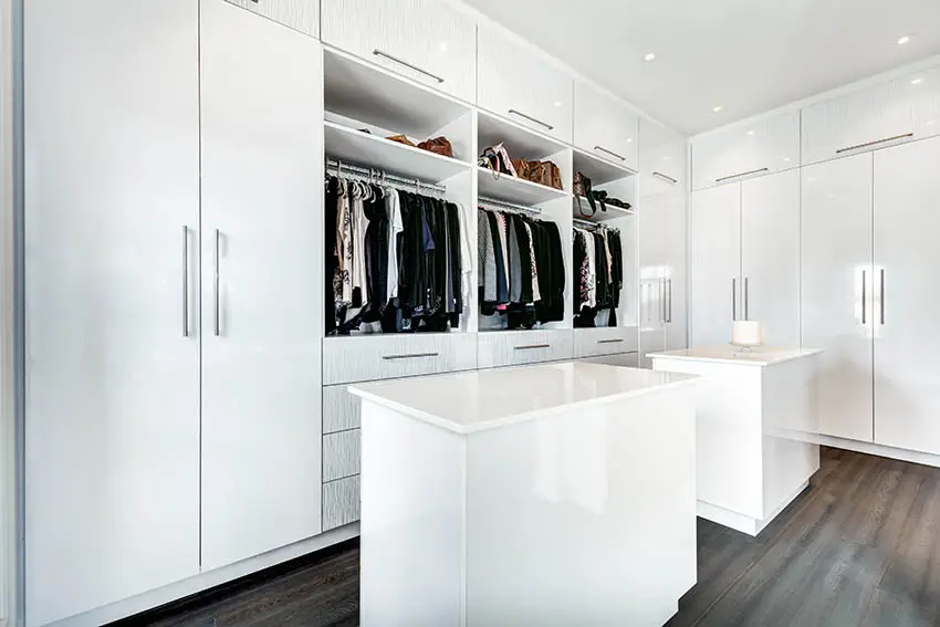 Modern walk in closet with two islands white quartz countertops and cabinets