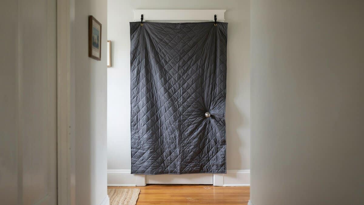 Quilted sound absorbing blanket hanging over a doorway in a hallway