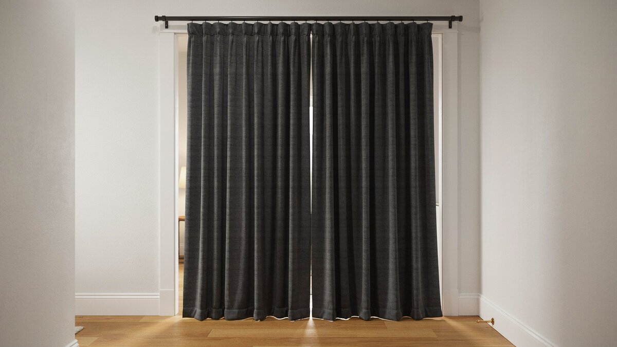 Heavy floor length soundproof curtain covering an interior doorway on a rod