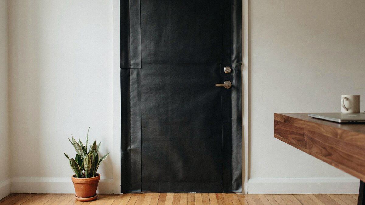 Dark soundproofing rubber sheets covering an interior door in a home office