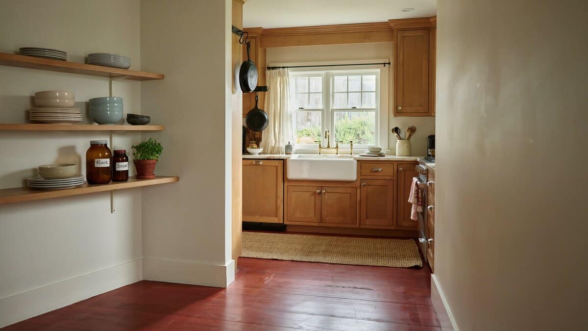 Traditional kitchen with red oak flooring seen through a doorway, oak cabinets, open shelves and a farmhouse sink