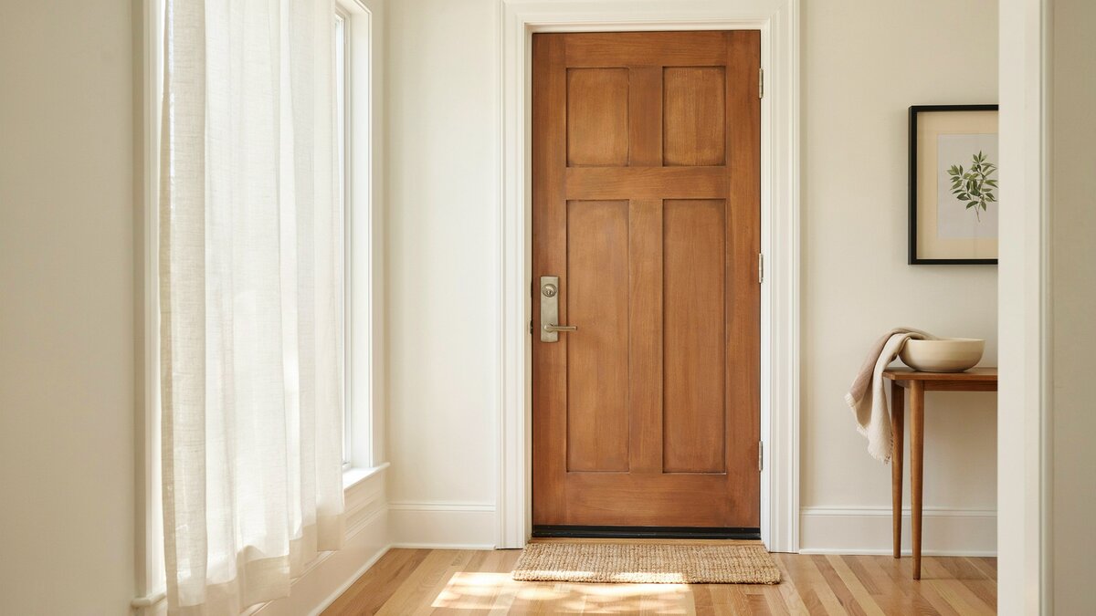 Solid wood front entry door with weatherstripping in a bright entryway