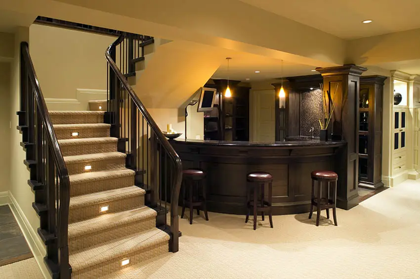 Home bar with curved wood countertop, staircase and bar stools