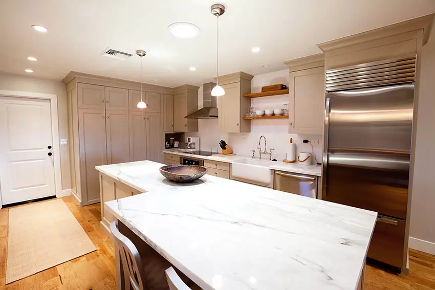 Kitchen with marble top island recessed and pendant lighting