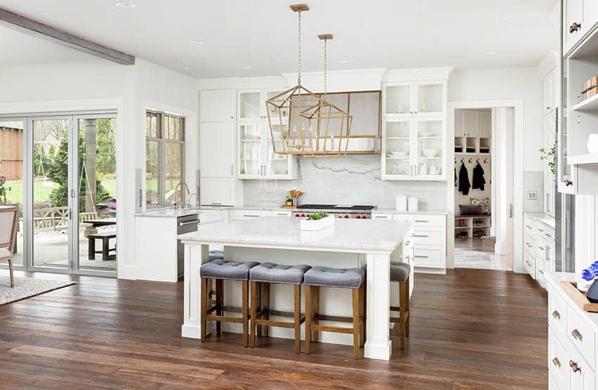 Contemporary kitchen with calacatta quartz backsplash countertops white cabinets wood flooring geometric chandeliers
