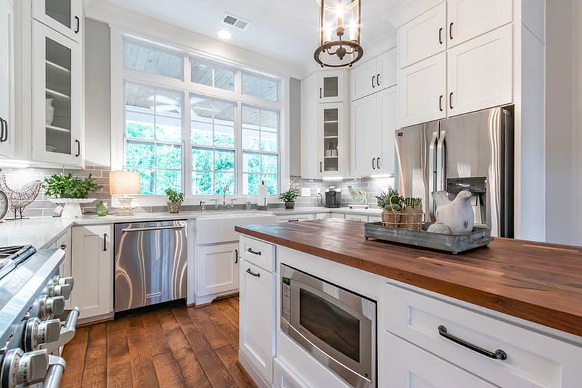 Kitchen with white cabinets hardware pulls butcher block island white quartz countertops