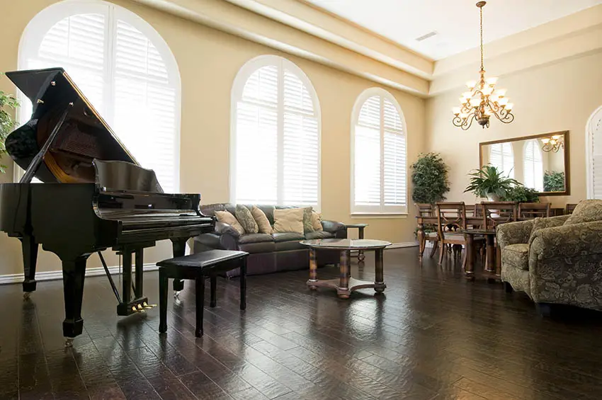 Room with baby grand piano, pastel yellow walls and brown colored furniture