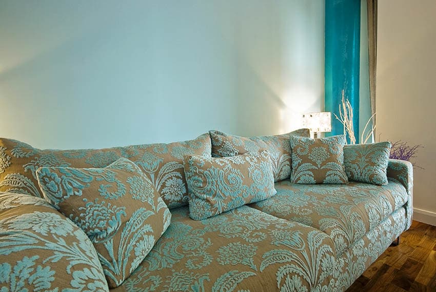 Living area with light hue blue details, beige wall and beige blue sofa