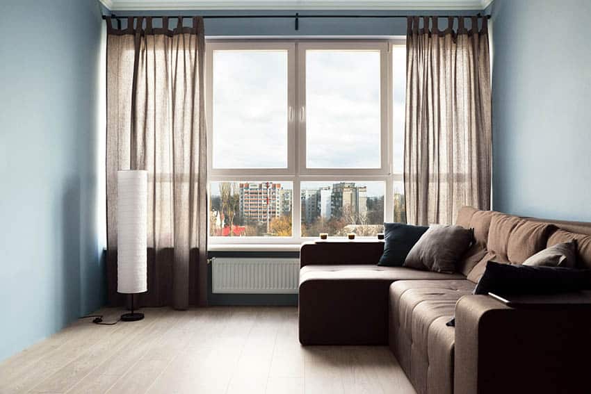 Room with muted color blue covered wall colors, brown sofa and brown curtains