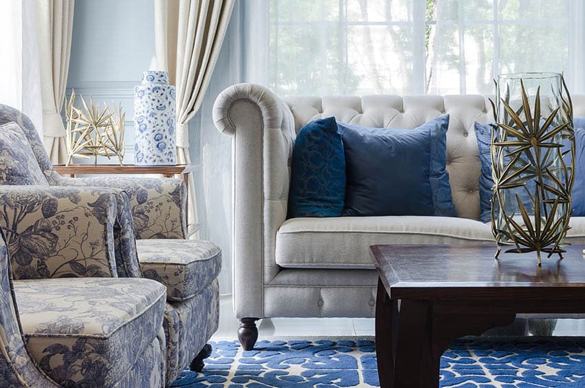 Living room with light blue wall paneling off white couch blue rug and blue white arm chairs