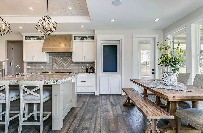 Modern farmhouse kitchen with light gray island white cabinets dark wood flooring rustic wood dining table