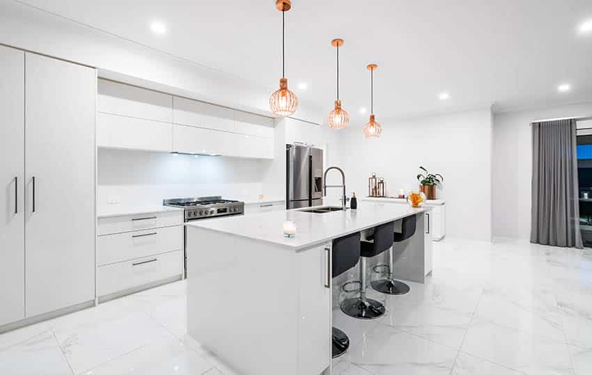 Modern kitchen island with sink across from stove white quartz and cabinets