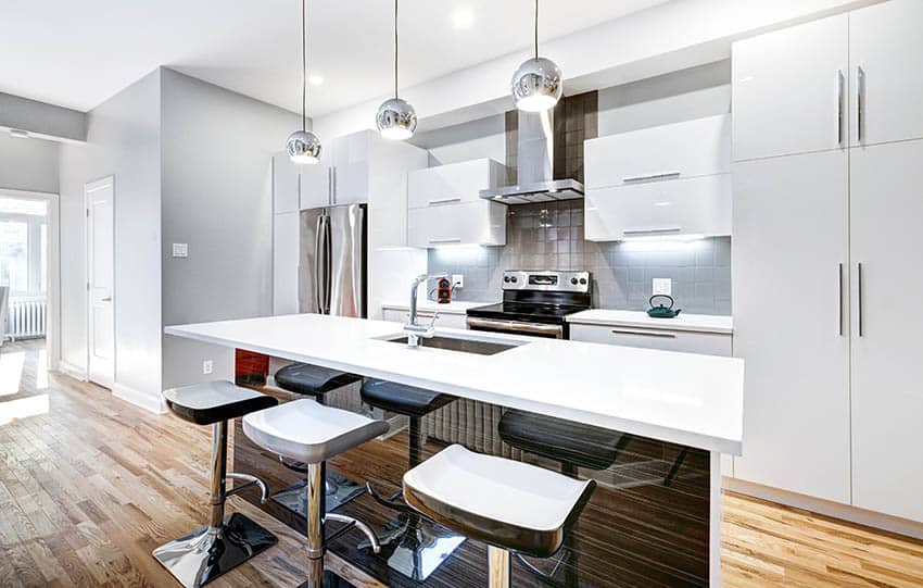 Modern kitchen island with sink quartz counters chrome pendant lights and barstools