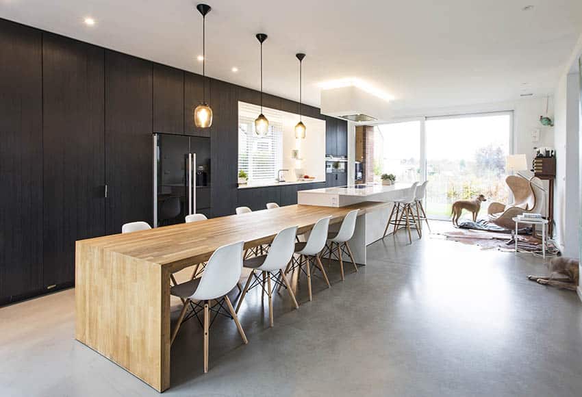 Modern kitchen with black cabinets long wood surface island concrete flooring