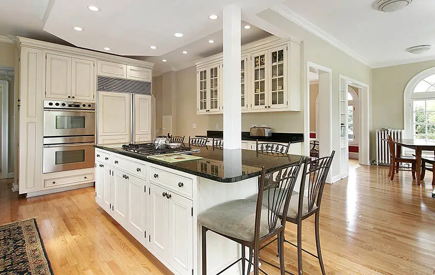 Traditional kitchen with white cabinets with knobs black granite countertops