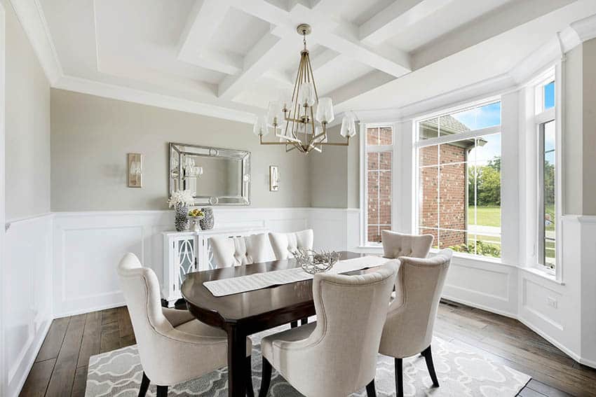 Beautiful wood dining table, fabric wing back chairs and white wainscoting