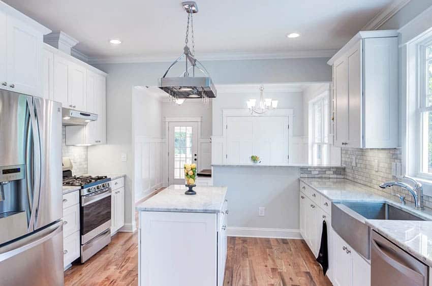 Southern cottage kitchen with white shaker cabinets marble countertops farmhouse sink