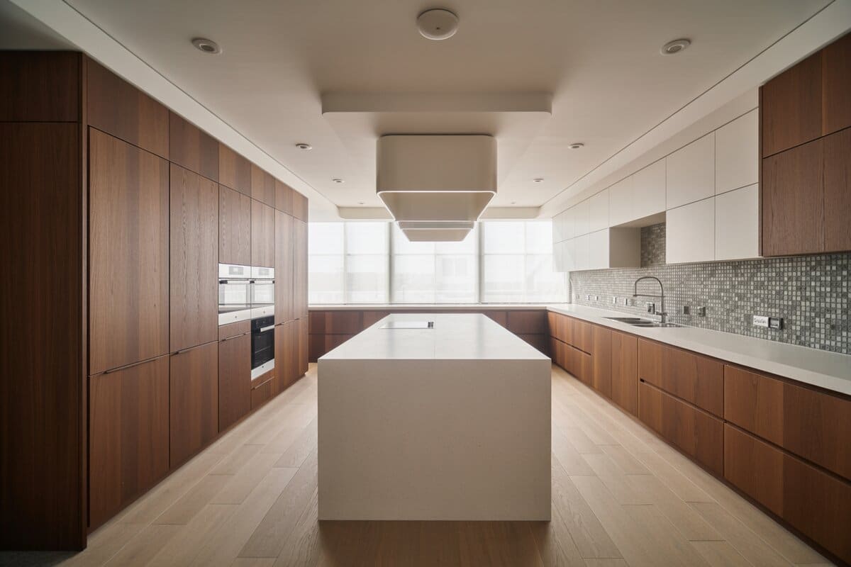Walnut cabinetry pairs with a white quartz waterfall island and silvery mosaic backsplash