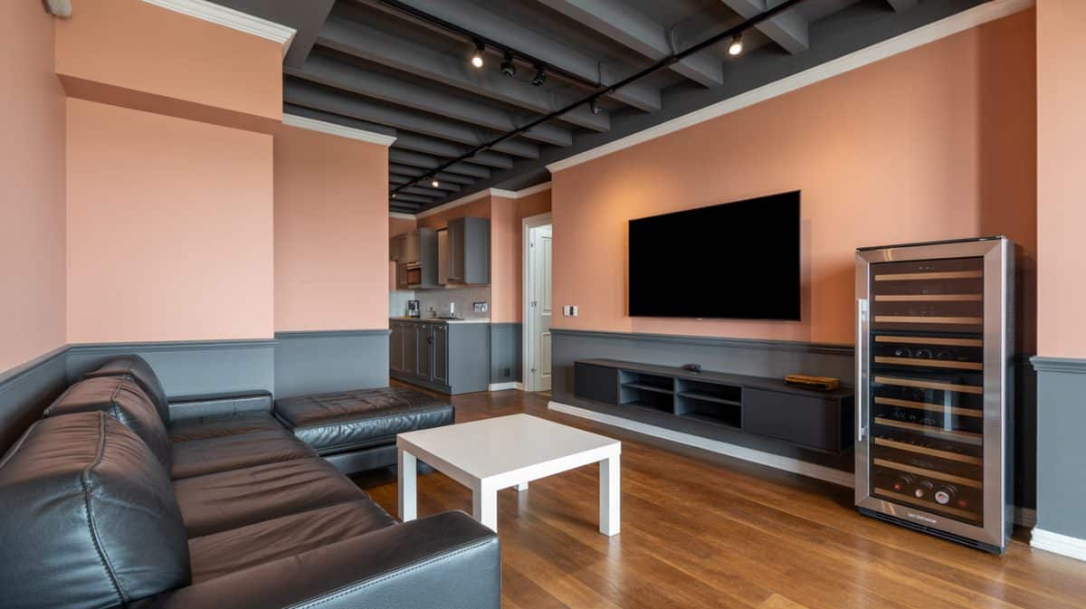 Bachelor masculine living room with track lighting, oversized dark leather sectional sofa, built-in wine fridge, and hardwood floors