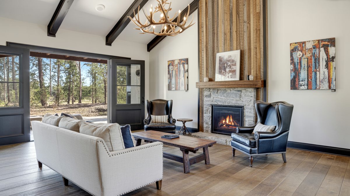 Transitional masculine living room with navy wingback chairs, reclaimed wood accent wall, and stone fireplace