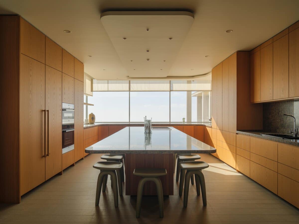 Oak cabinets frame a granite island with tucked stools below a curved view window