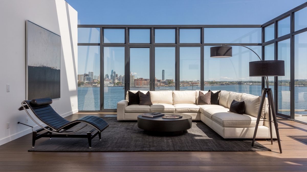 Modern penthouse masculine living room with floor-to-ceiling glass walls, panoramic city skyline view, and cream sectional