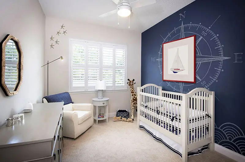 Baby nursery with crib dresser arm chair nautical accent wall