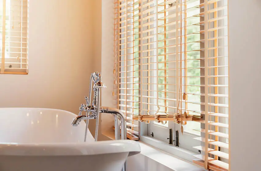 Bathroom with faux wood blinds above tub