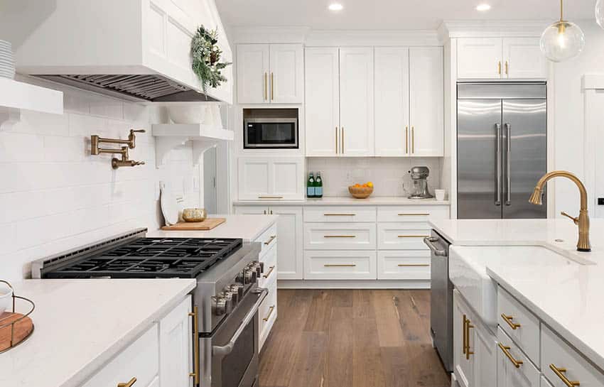 White Kitchen with brass faucet over stove top and farmhouse sink