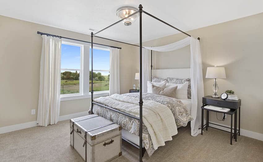 Bedroom with four post bed, beige wall paint and white curtains