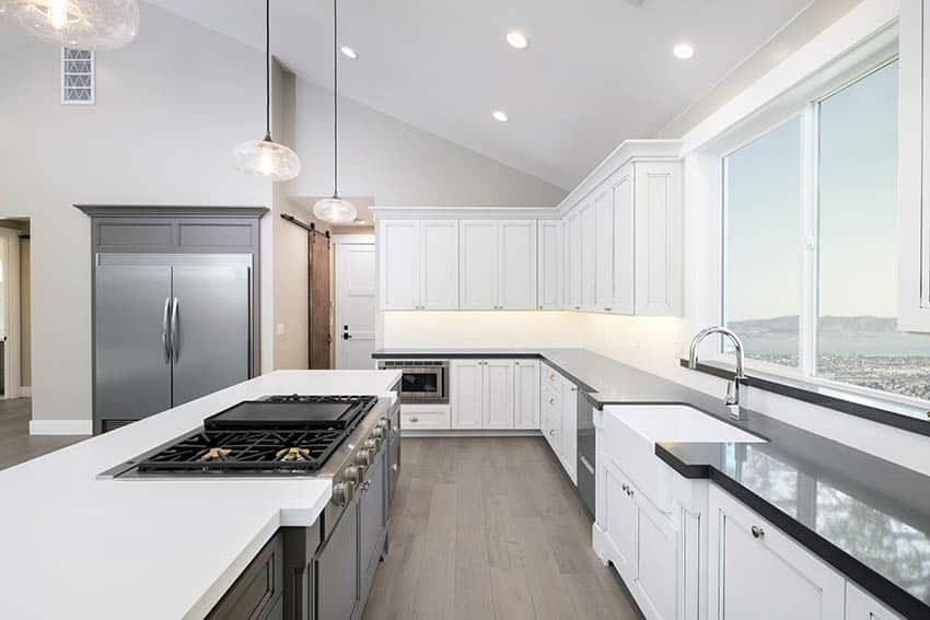 Contemporary kitchen with black and white countertops with black island and vaulted ceiling