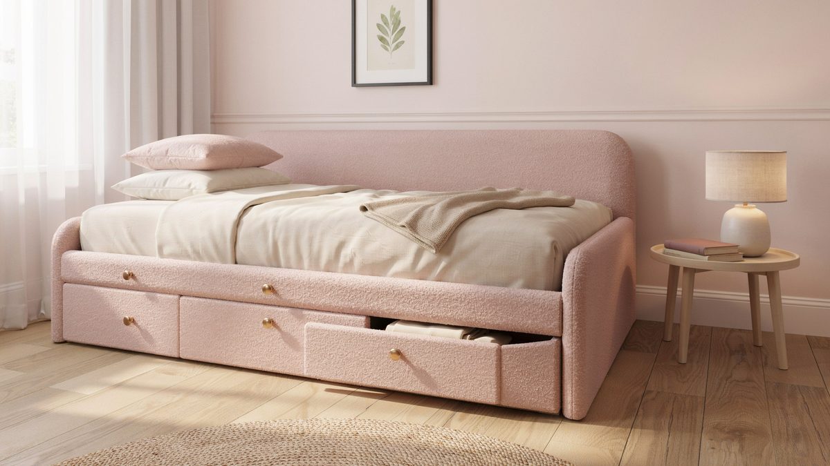 Pink upholstered divan bed with three storage drawers in a soft girls room