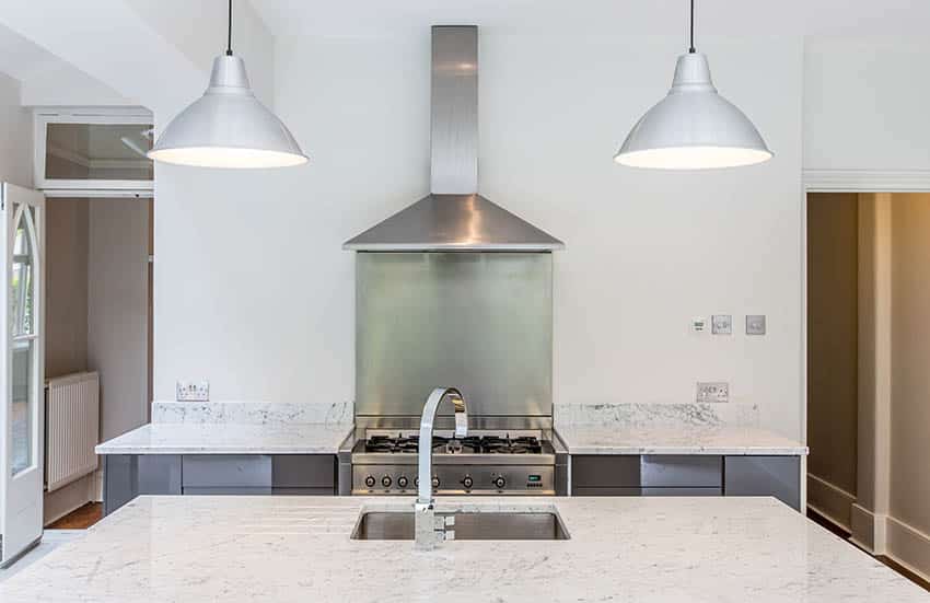 Two hanging lights with black cord and a range hood in the background