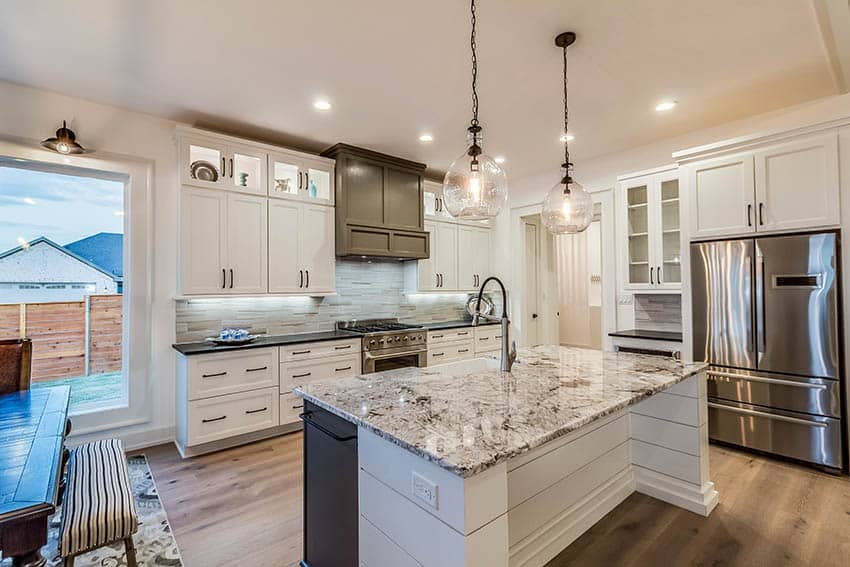 Island with granite countertops, glass above counter lights and dining chairs