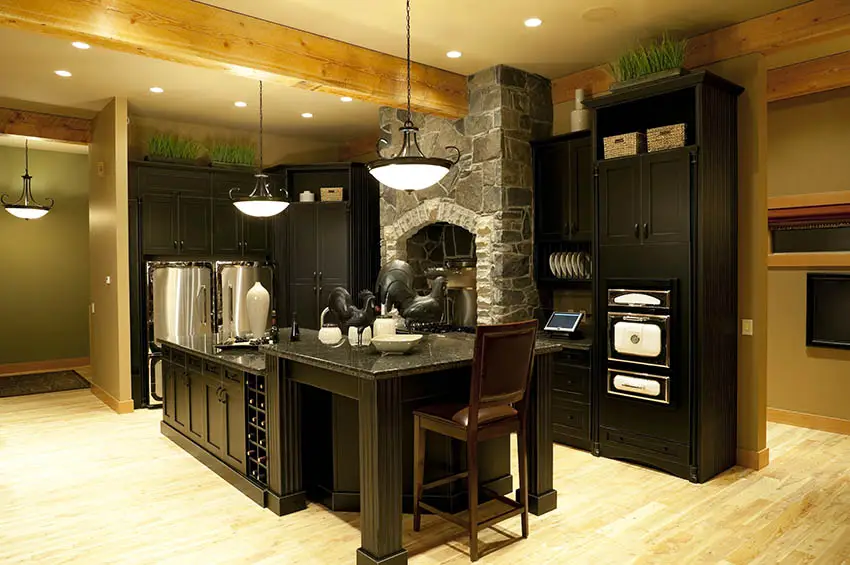 kitchen-with-two-tier-island-black-cabinets-stone-stove-surround-light-wood-flooring