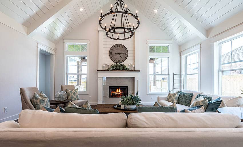 Cathedral ceiling, accent cushions and large wall clock on fireplace mantle