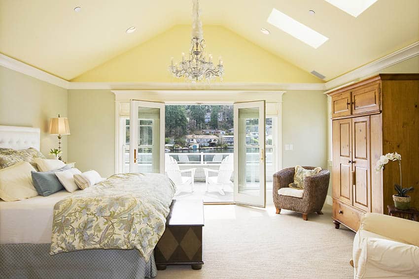 Luxury bedroom with beige wool carpet vaulted ceiling skylights and chandelier