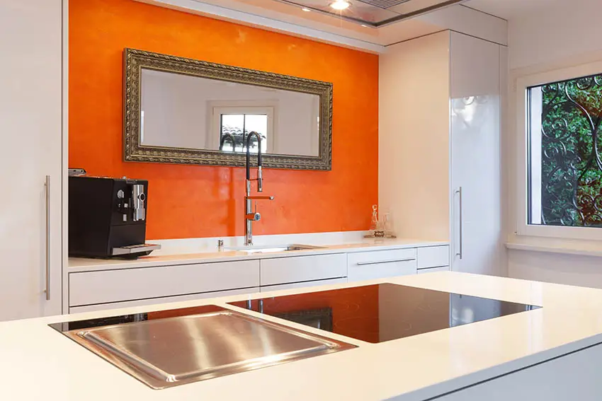 Kitchen with orange accent wall with mirror