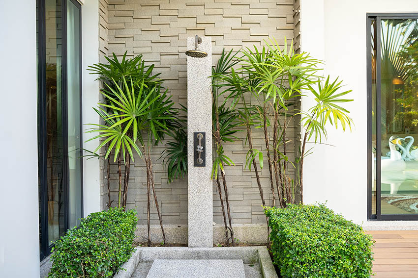 Outdoor shower faucet head next to modern home