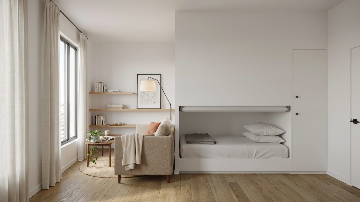 Studio apartment with a white murphy bed folded down beside a small armchair
