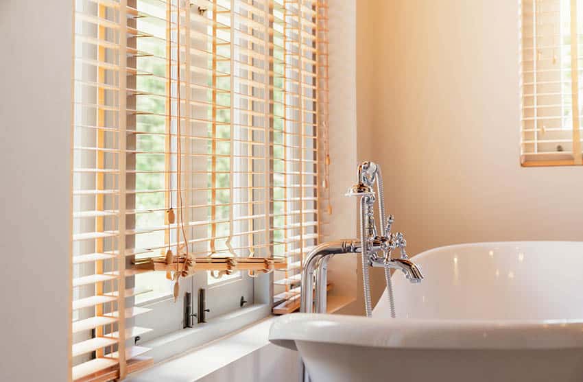 Bathroom with window blinds above tub