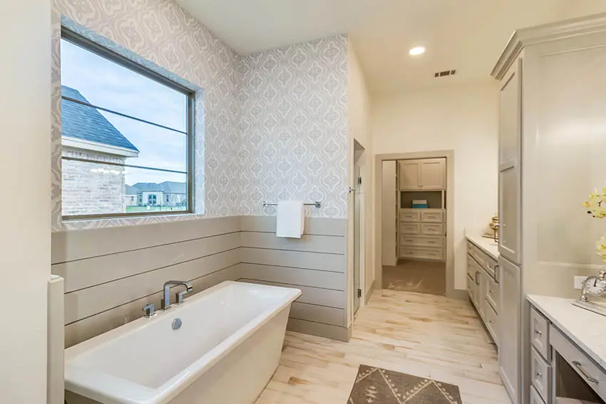 Bathroom with wood look vinyl sheet flooring grey shiplap walls and patterned wallpaper
