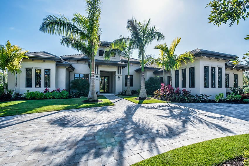 Contemporary home with paver driveway palm trees tropical landscaping